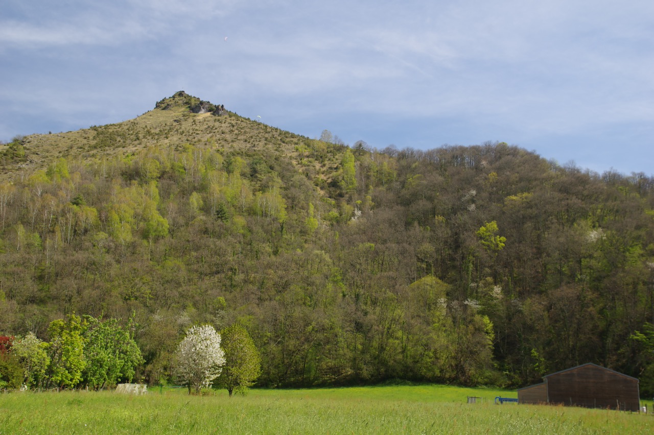 The mountain behind the SETE in Moulis in a spring, green setting, with paragliders taking off